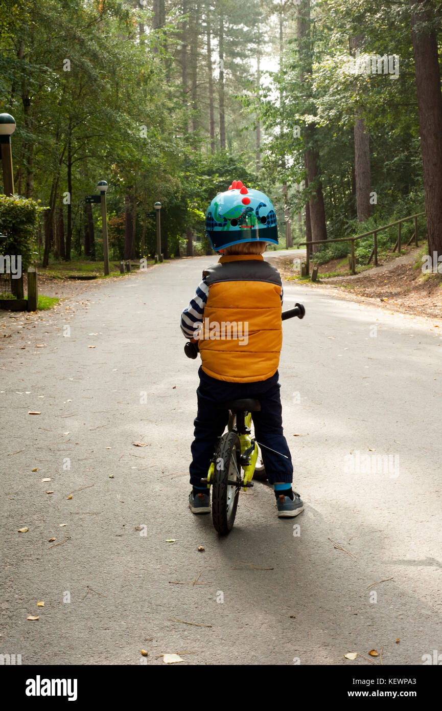 Kleiner Junge mit dem Fahrrad hinunter einen Waldweg Stockfoto