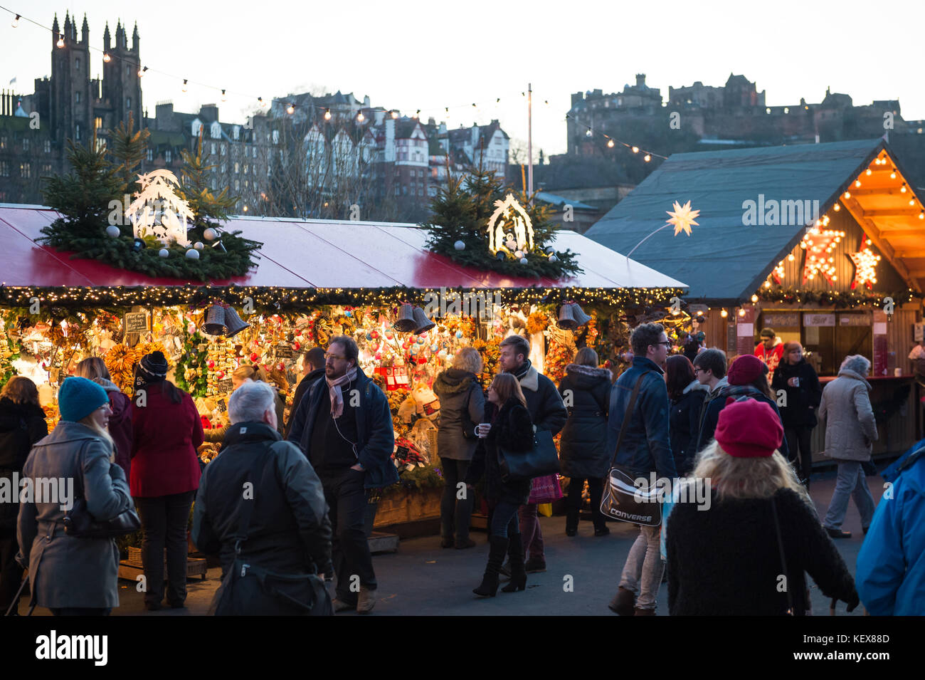 EDINBURGH, SCHOTTLAND, Vereinigtes Königreich – 8. Dezember 2014 – Menschen gehen an den Ständen des deutschen weihnachtsmarktes in Edinburgh, Schottland, Großbritannien, mit Schloss in Edinburgh Stockfoto