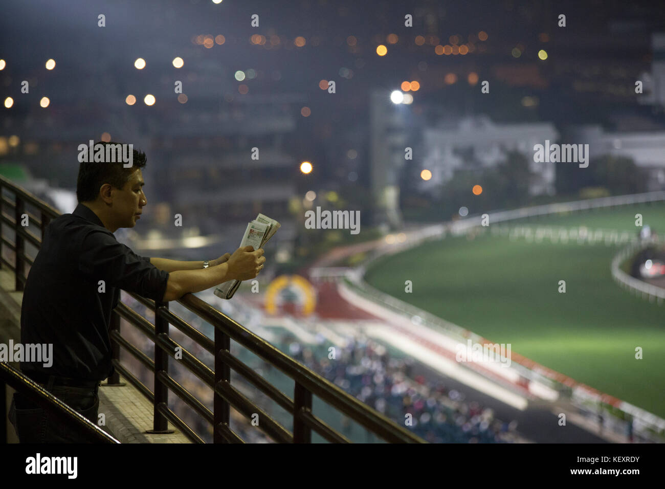 Foto von Mann beim Lesen von Wetten auf Pferderennbahn, Hongkong, China Stockfoto