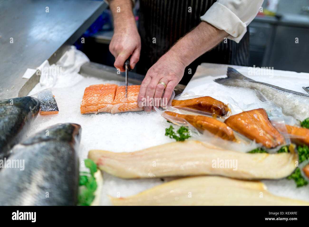 Britische fish monger Zerteilen, Filetieren oder Schneiden frische slamon auf Eis auf einem Markt Personal in Yorkshire, England Stockfoto