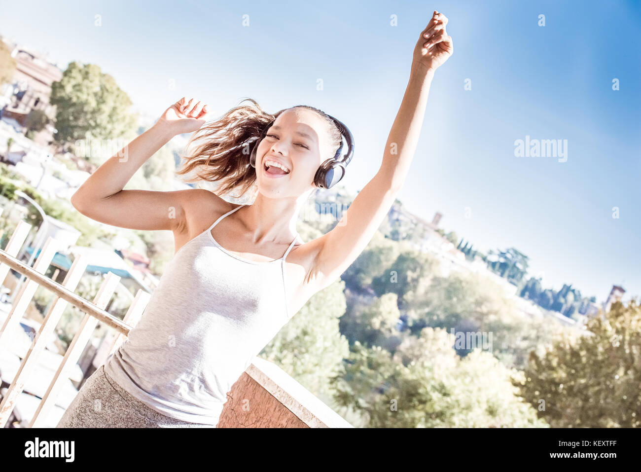 Jungen asiatischen Teenager Frau Outdoor Portrait geschlossenen Augen Sonnenlicht Freude und begeisterten Leidenschaft tanzen und lächelnd mit Kopfhörer Stockfoto