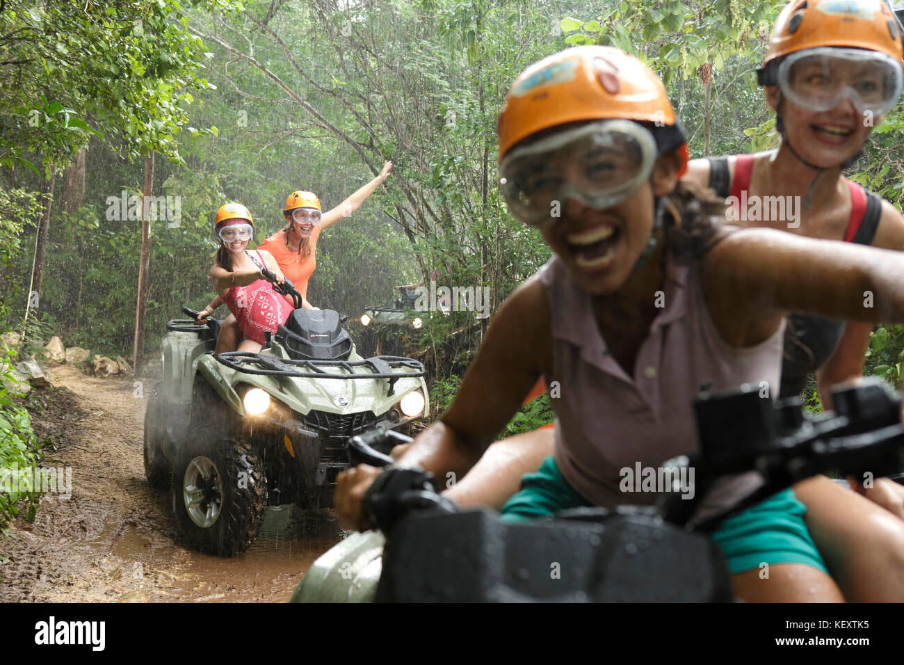 Frauen lachen während der Fahrt Quad Bikes in Emotionen Native Park bei Regen, Quintana Roo, Mexiko Stockfoto