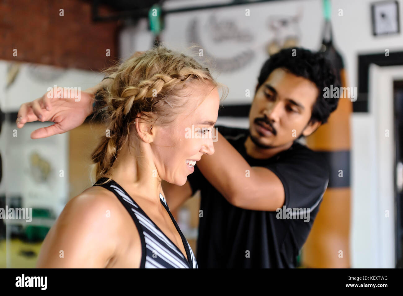 Foto der jungen Frau die Hilfe erstreckt sich von Trainer im Fitnessstudio, Seminyak, Bali, Indonesien Stockfoto