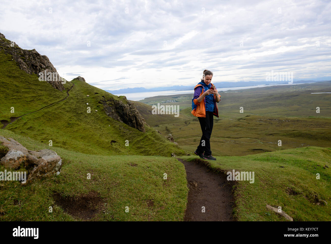 Schottisches Hochland, Isle of Skye. Cuith-Raing oder Quiraing. Wanderer macht ein Panoramabild mit ihrem Handy. Stockfoto