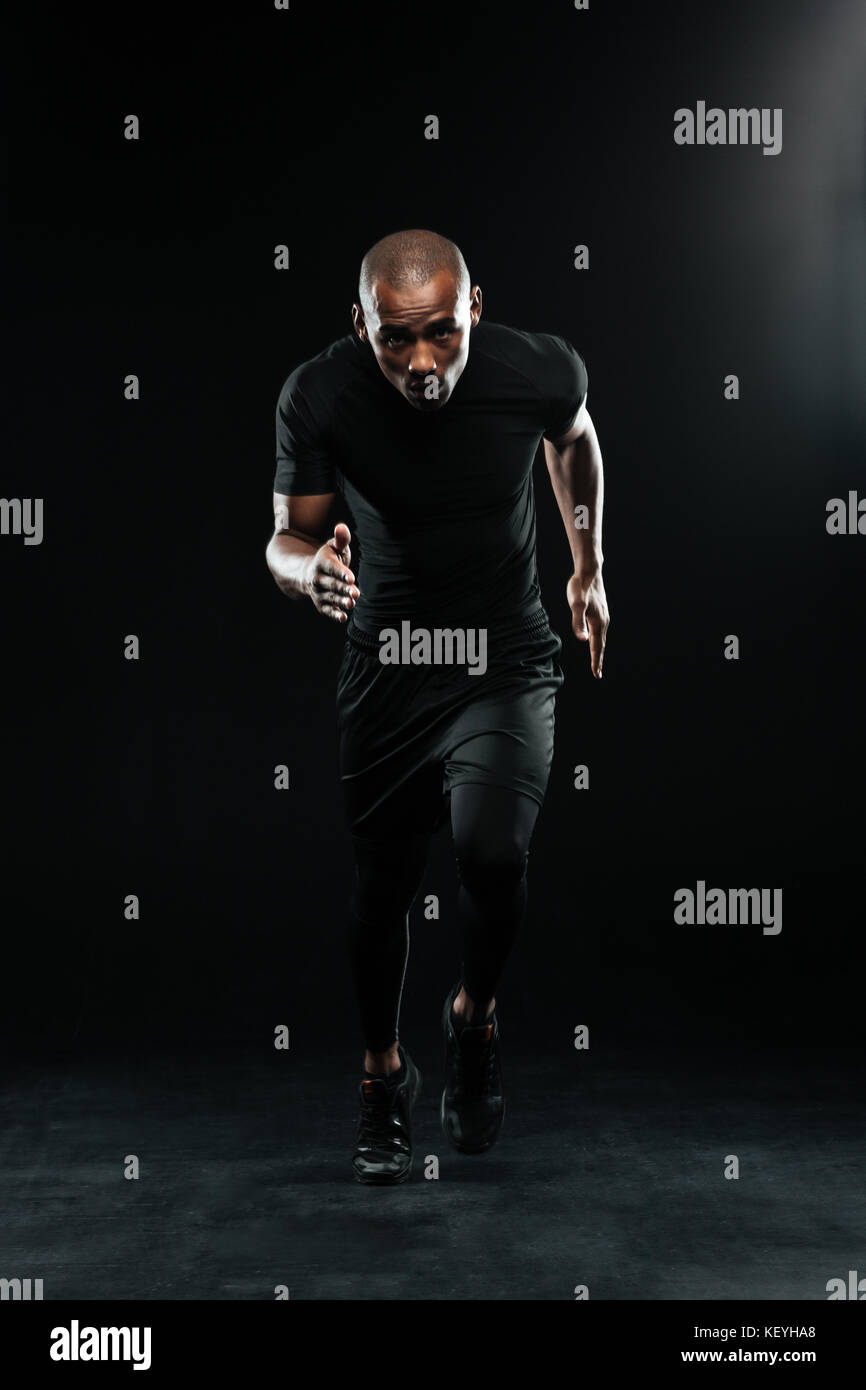 Voller Körper Foto von afro-amerikanische laufender Mann, von der Kamera suchen, auf schwarzem Hintergrund Stockfoto