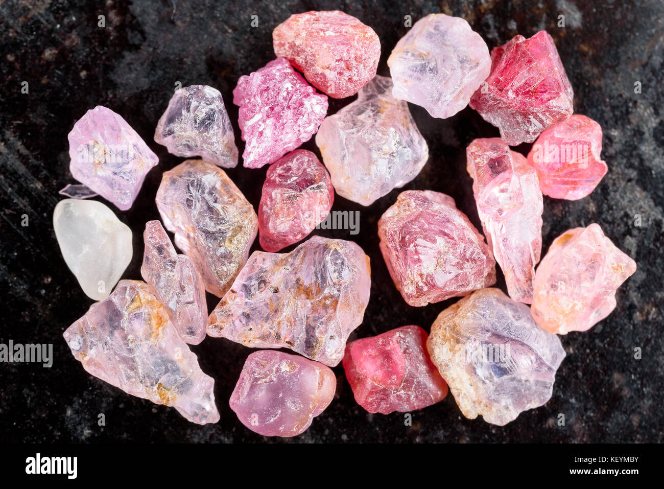 Sammlung von rosa und rote rauhe uncut Spinell Edelsteine auf schwarzen Stein Schiefer. Stockfoto