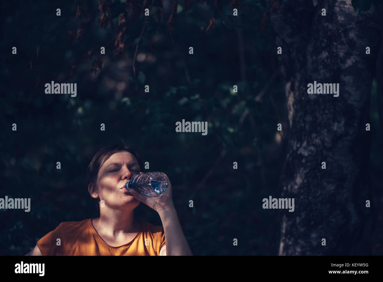 Frau trinkt Wasser draußen. durstig nach kaukasisch Weiblich erfrischend nach einem langen Spaziergang durch den Park auf sonnigen Sommertag, ungewöhnliche Framing, selektive Stockfoto