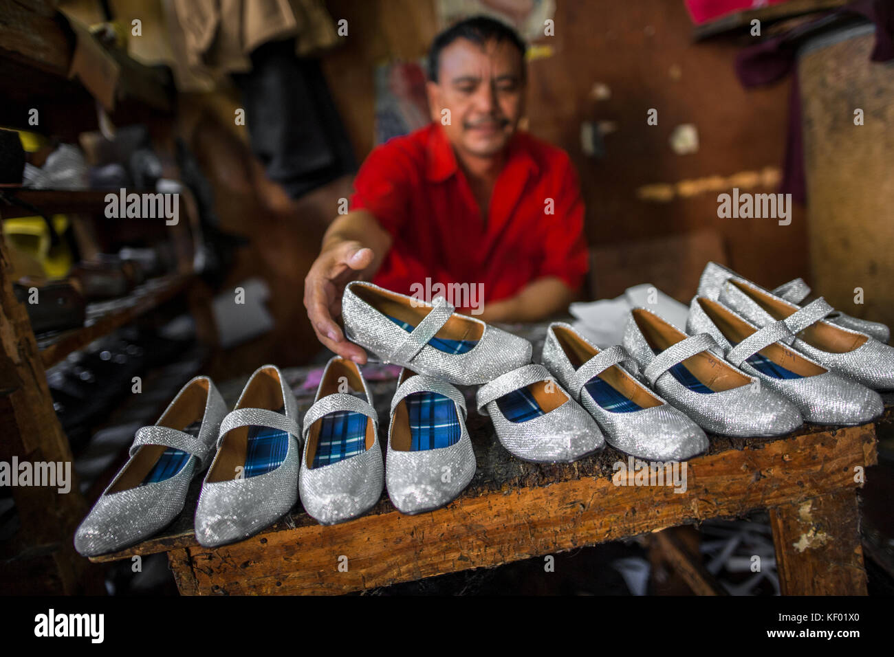 Eine salvadorianische Schuster zeigt neu gemachten Paare Silber glitter Girl's Schuhe auf der Werkbank in einem Schuh macht Workshop in San Salvador, El salvado Stockfoto