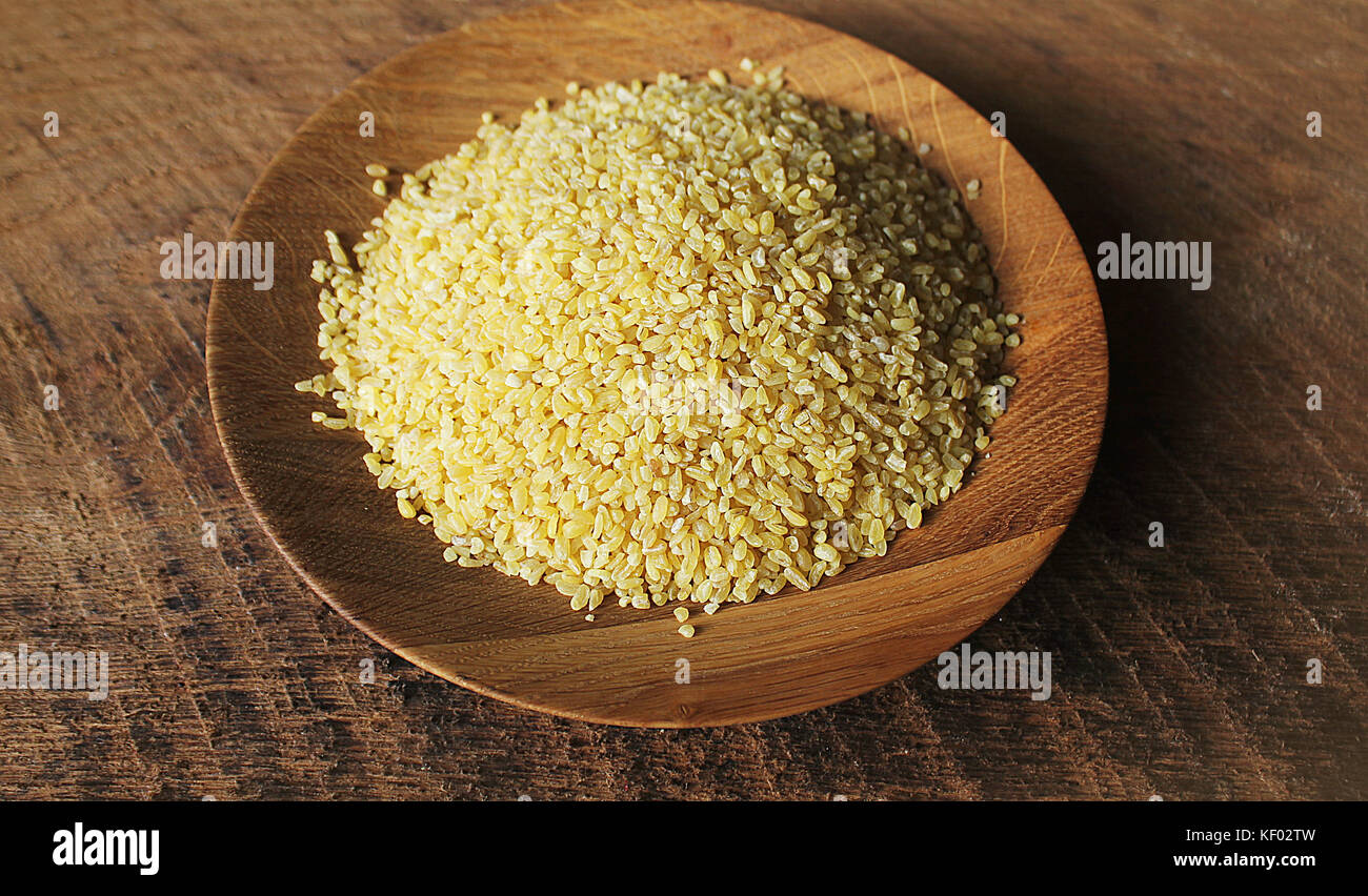 Trockene Bulgur weizen in Houten isoliert verschüttete Bulgur Stockfoto