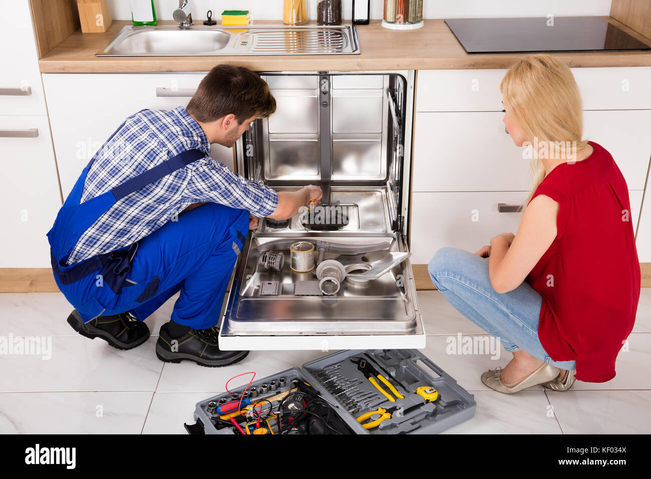 Junge Frau schlosser Reparatur Geschirrspüler in der Küche auf der Suche Stockfoto