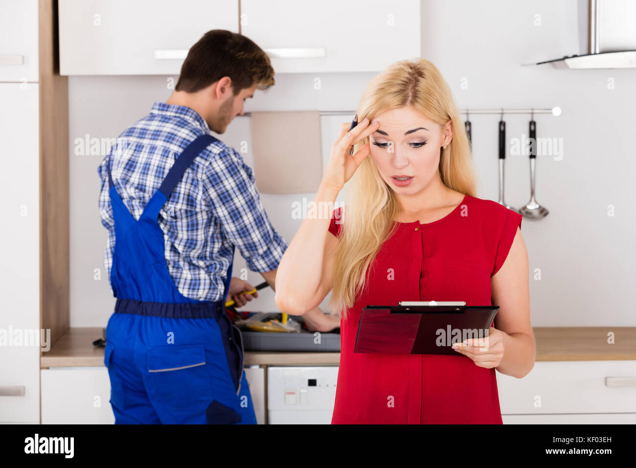 Junge frustrierte Frau an riesige Rechnung von klempner stehen in der Küche Stockfoto