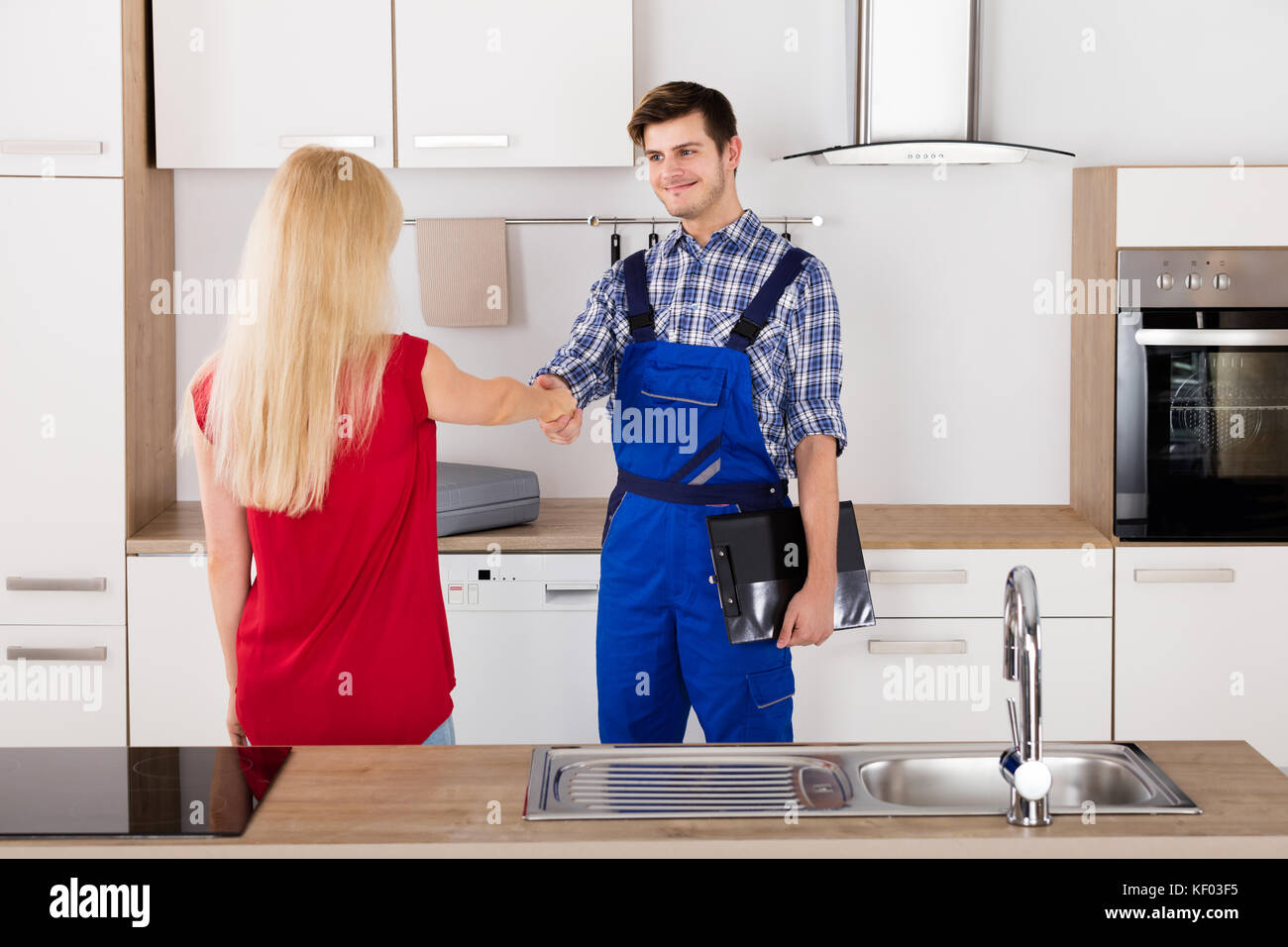Lächelnd Hausfrau Frau Händeschütteln mit männlichen Klempner nach fix in der Küche Stockfoto