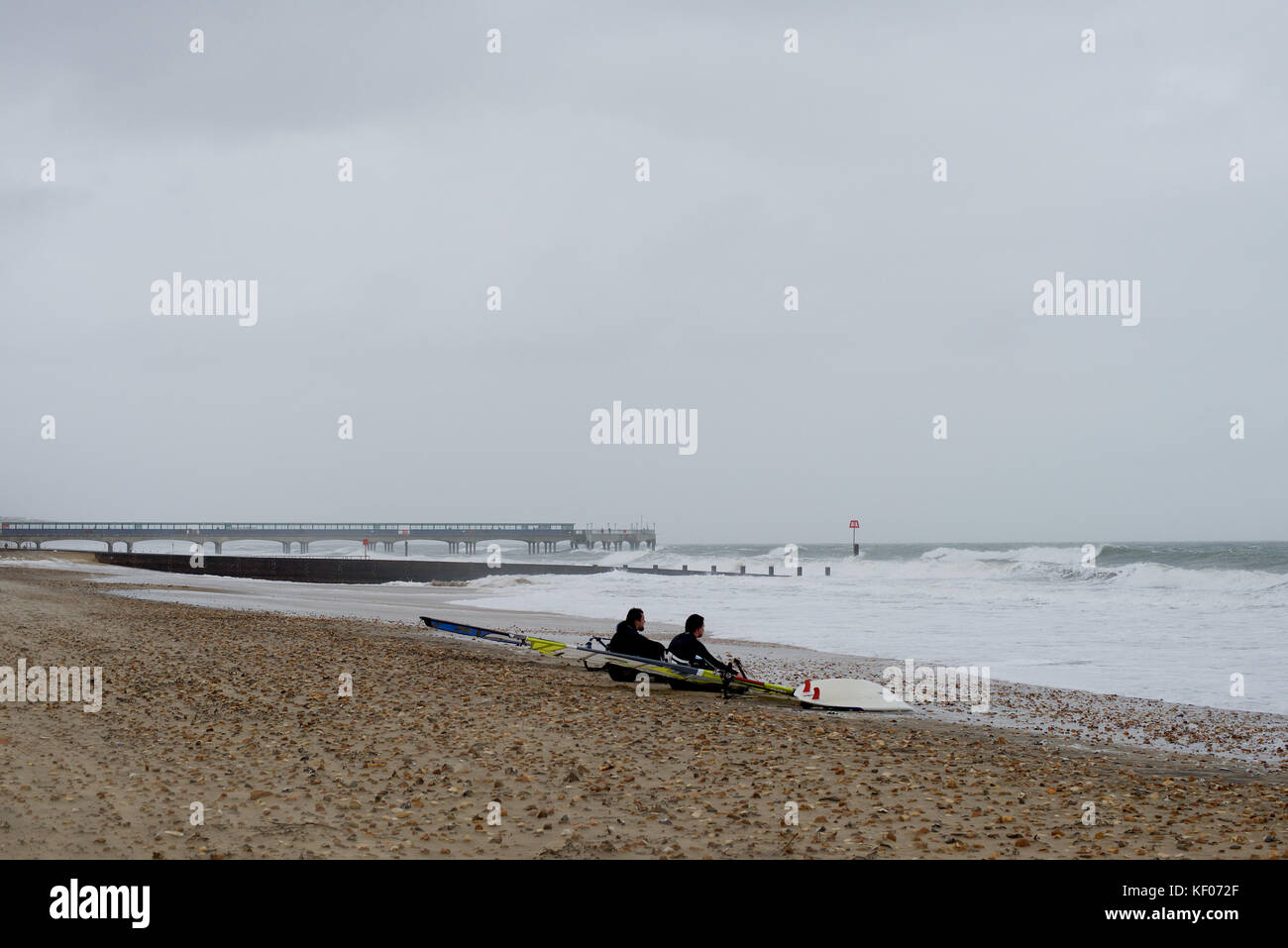 Zwei Windsurfer betrachten das rauhe Meer in Bournemouth Stockfoto