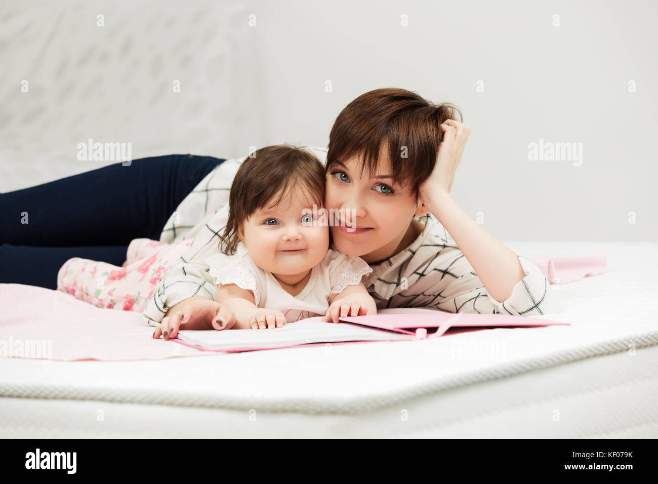 Mutter und Baby Mädchen das Lesen eines Buches auf dem Bett Stockfoto