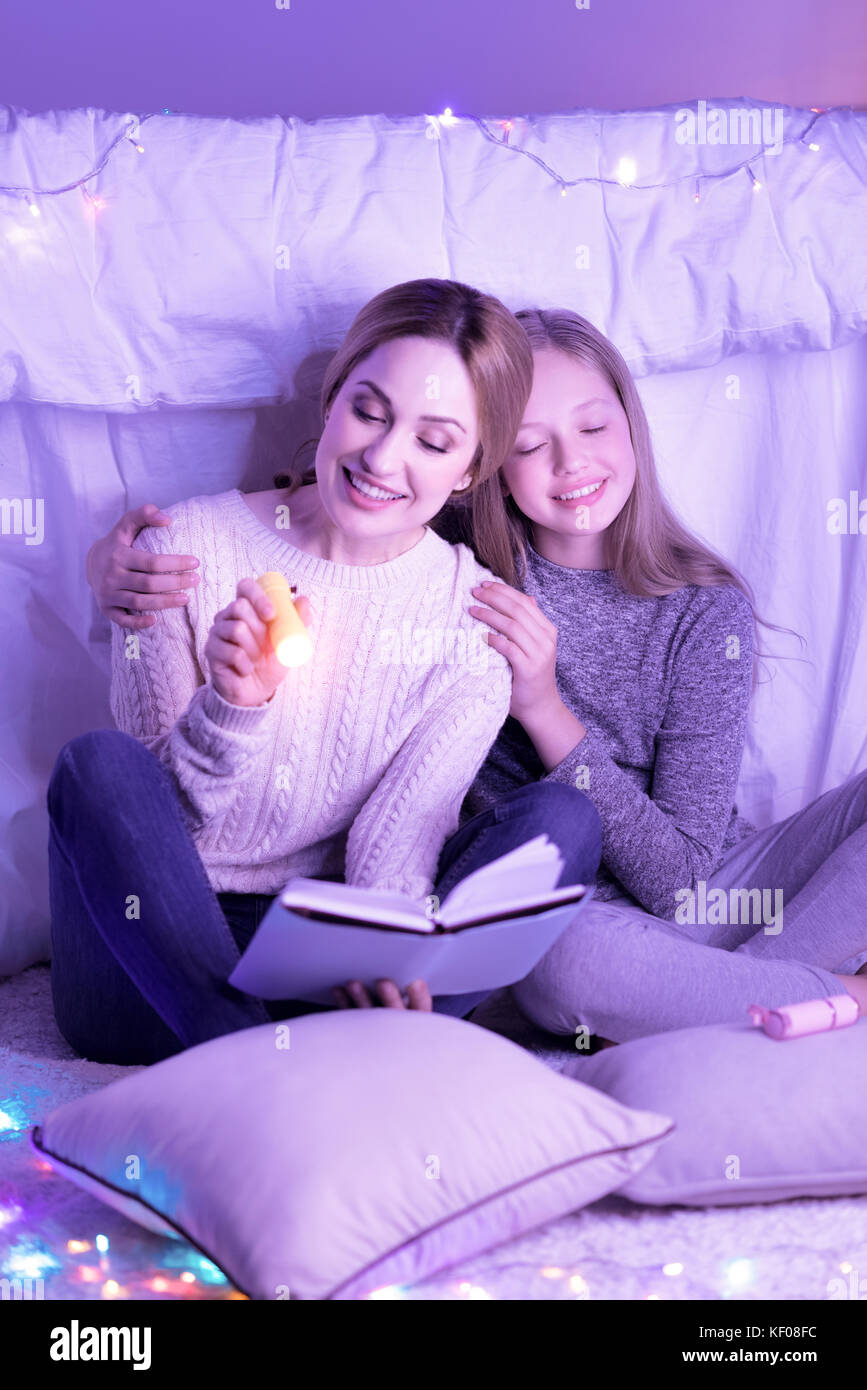 Liebevolle Mutter und Tochter umarmen beim Lesen Stockfoto