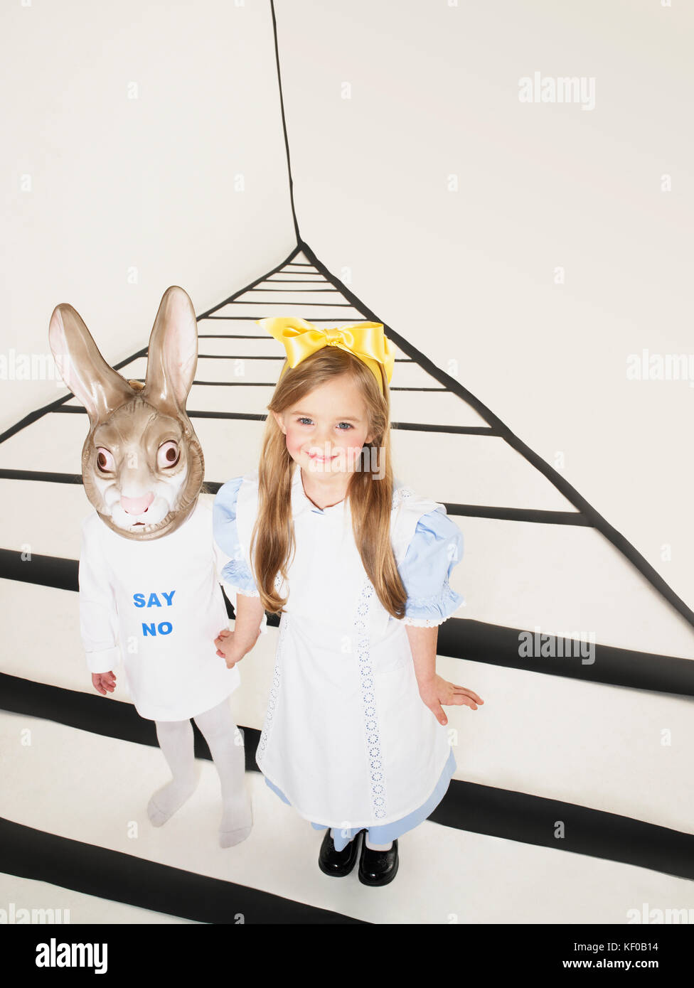 Portrait von lächelnden Mädchen, wie Alice im Wunderland Hand in Hand mit Mädchen mit Hase Maske verkleidet Stockfoto