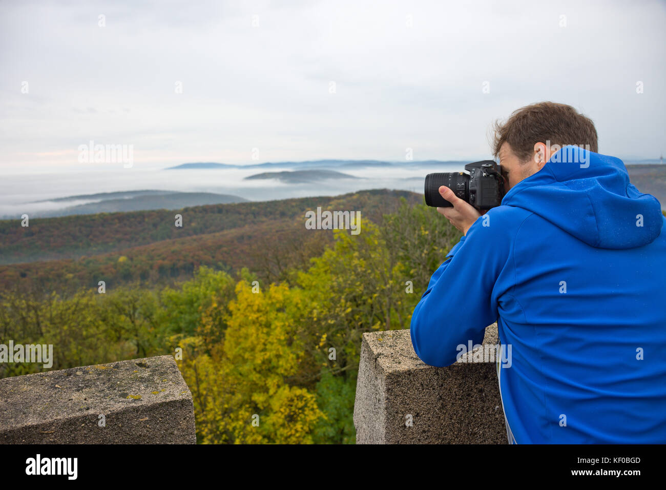 Fotograf nimmt ein Foto auf einem Berg im Wienerwald auf einem nebligen und trüben Herbsttag. Stockfoto