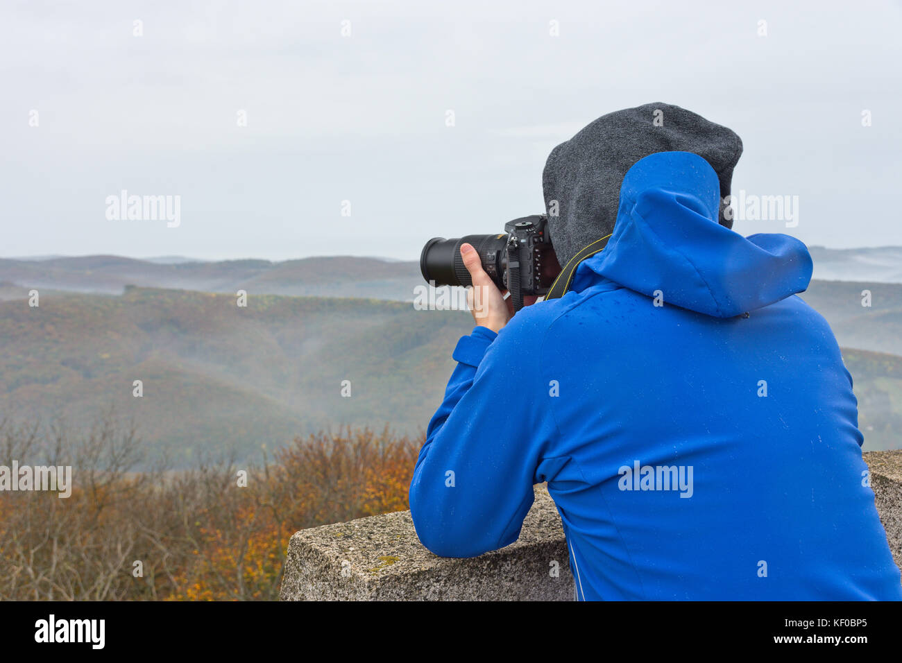 Fotograf nimmt ein Foto auf einem Berg im Wienerwald auf einem nebligen und trüben Herbsttag. Stockfoto