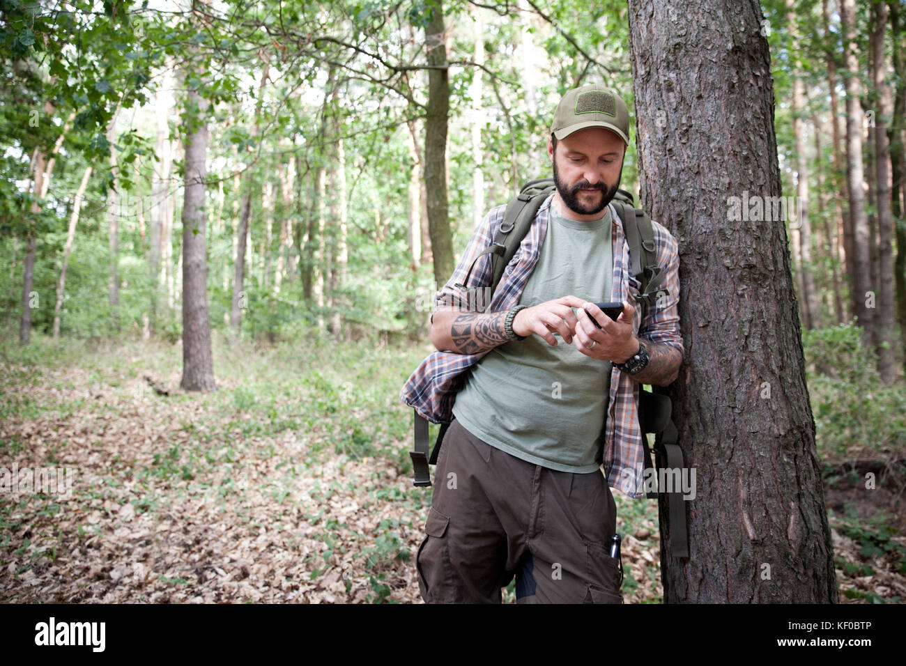 Mann mit Rucksack auf eine Wanderung im Wald mit Handy Stockfoto