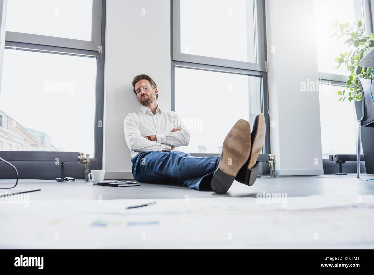 Geschäftsmann entspannen auf dem Fußboden seines Büros Stockfoto