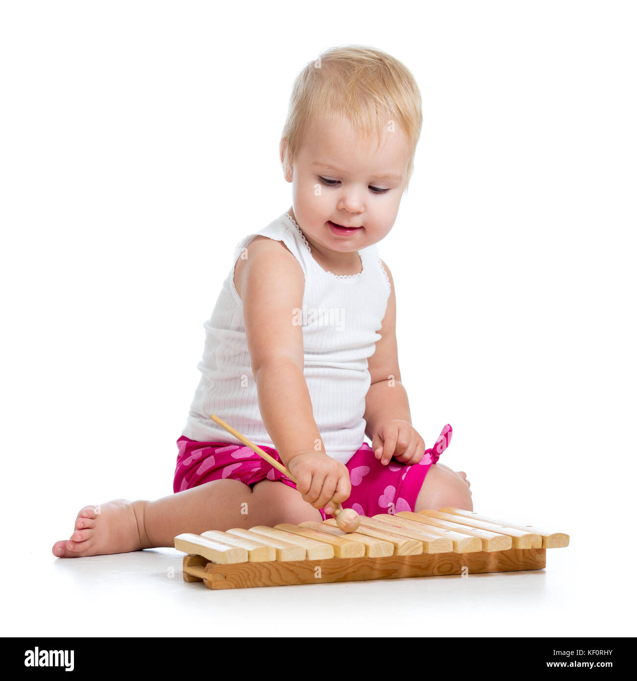 Kleines Mädchen mit Begeisterung spielen auf Xylophon isoliert auf Weiss. Stockfoto