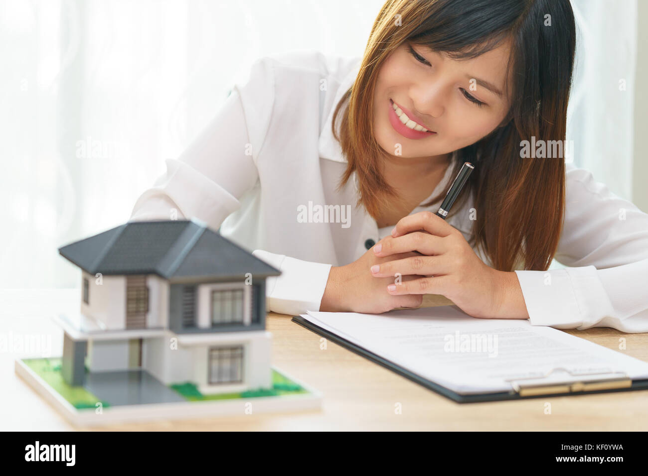 Lächeln Frau zu Hause suchen und fertig Vertrag für Investitionen zur Anmeldung Home erfüllen Stockfoto