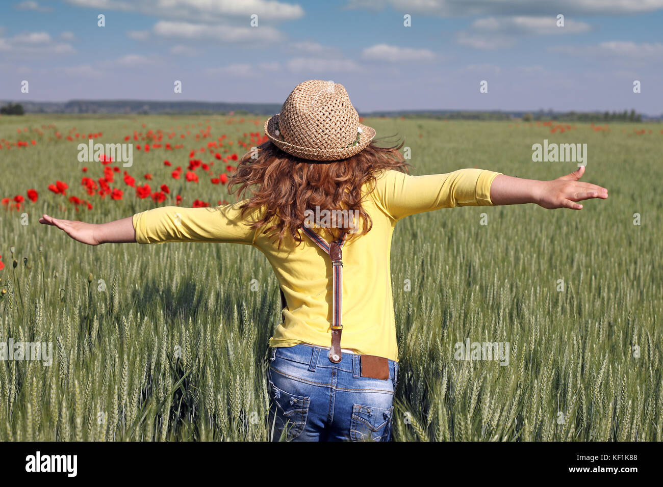 Kleines Mädchen läuft durch ein Feld von grüner Weizen Stockfoto