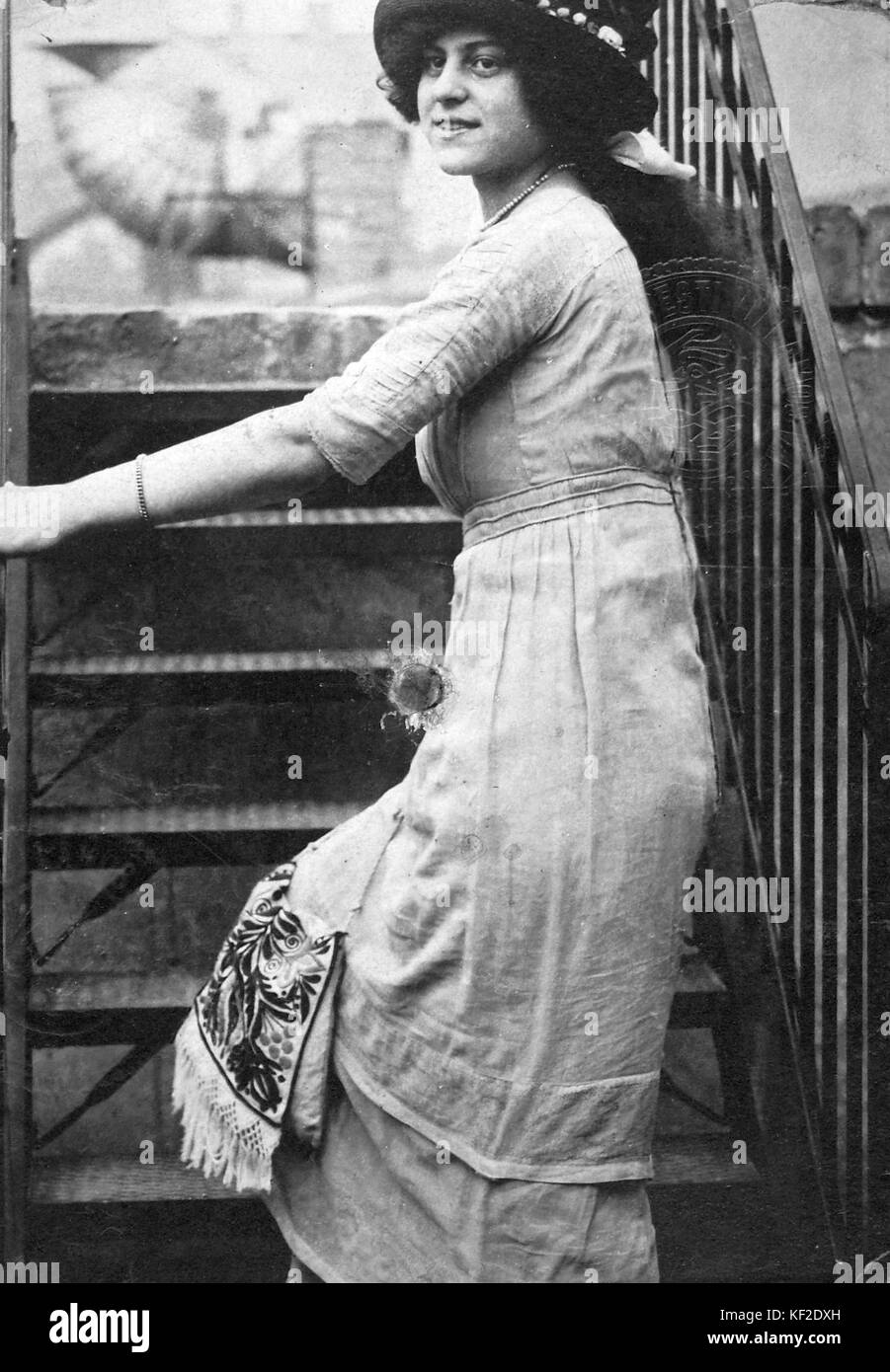 Dieses Foto zeigt eine Frau, die eine Treppe hinaufsteigt, in modischer Kleidung, die Modetrends des frühen 20. Jahrhunderts und die Bedeutung der Bewegung in der Modefotografie demonstriert. Stockfoto