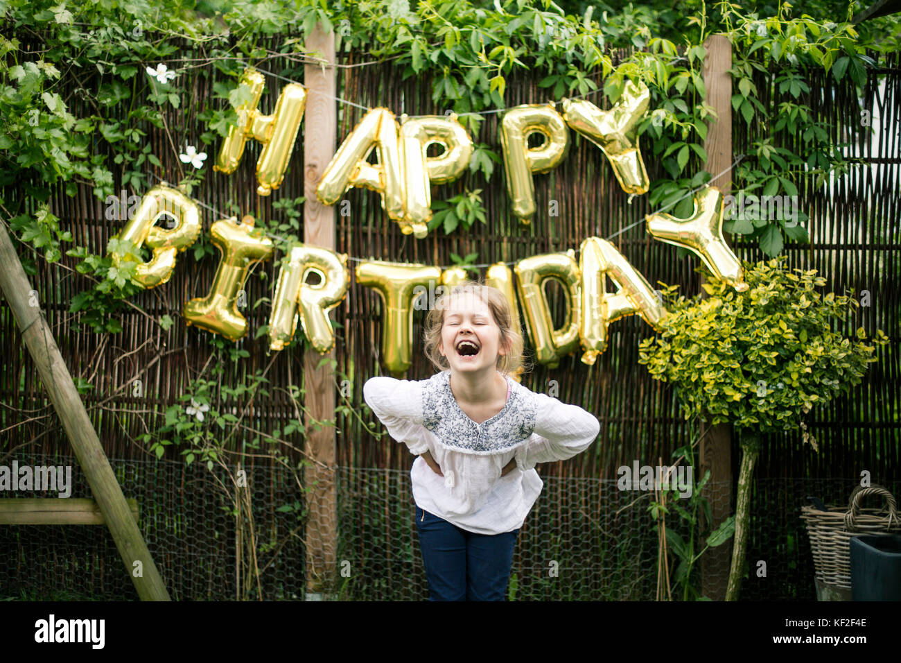 Portrait des lachenden Mädchens im Garten mit Dekoration für die Geburtstagsparty im Hintergrund Stockfoto