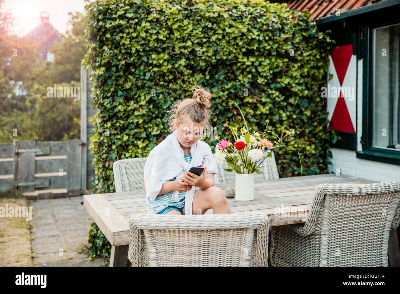 Mädchen sitzen auf der Terrasse Tabelle mit Handy Stockfoto