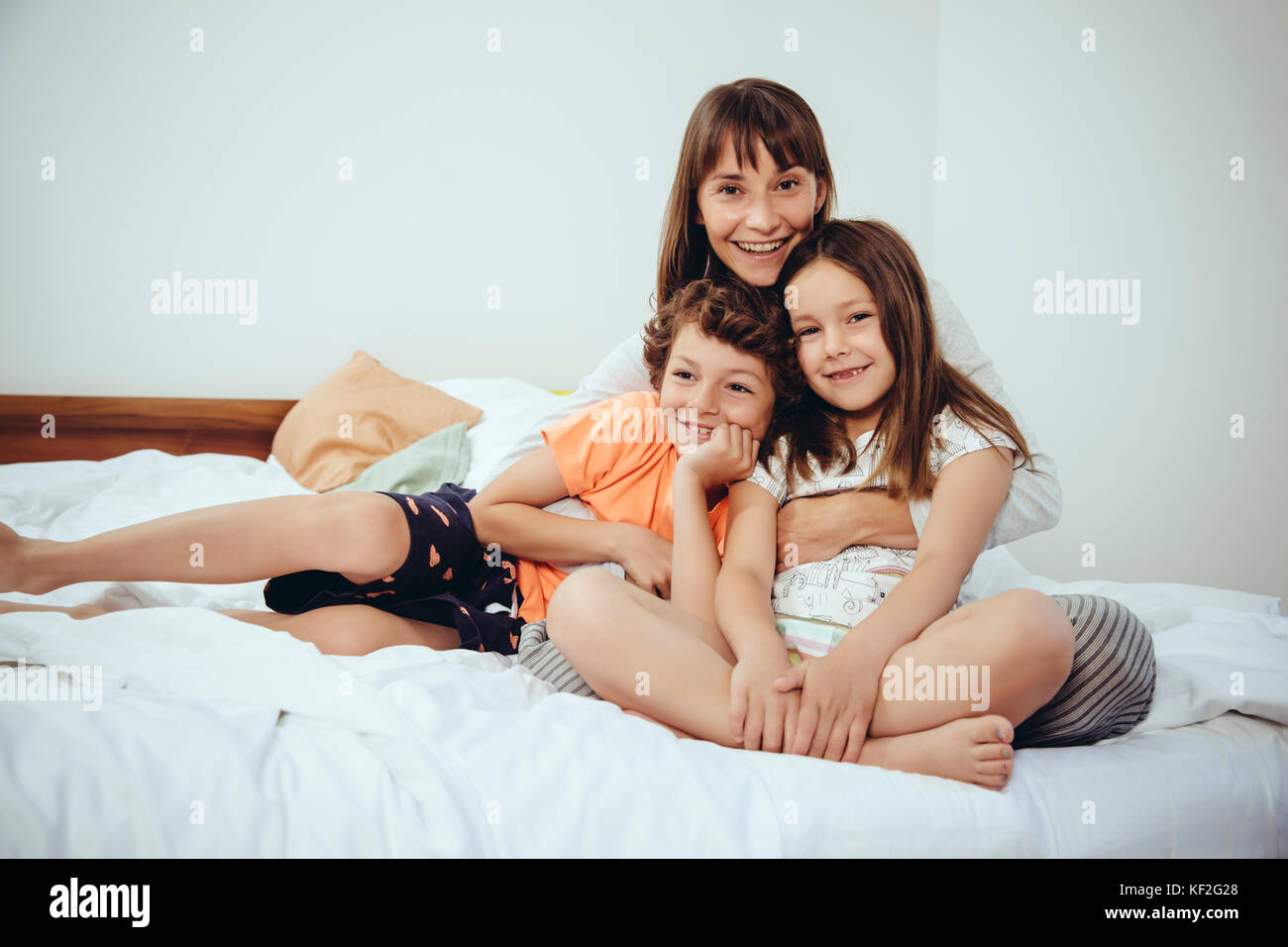 Glückliche Mutter im Bett mit ihrer Tochter und ihrem Sohn Stockfoto