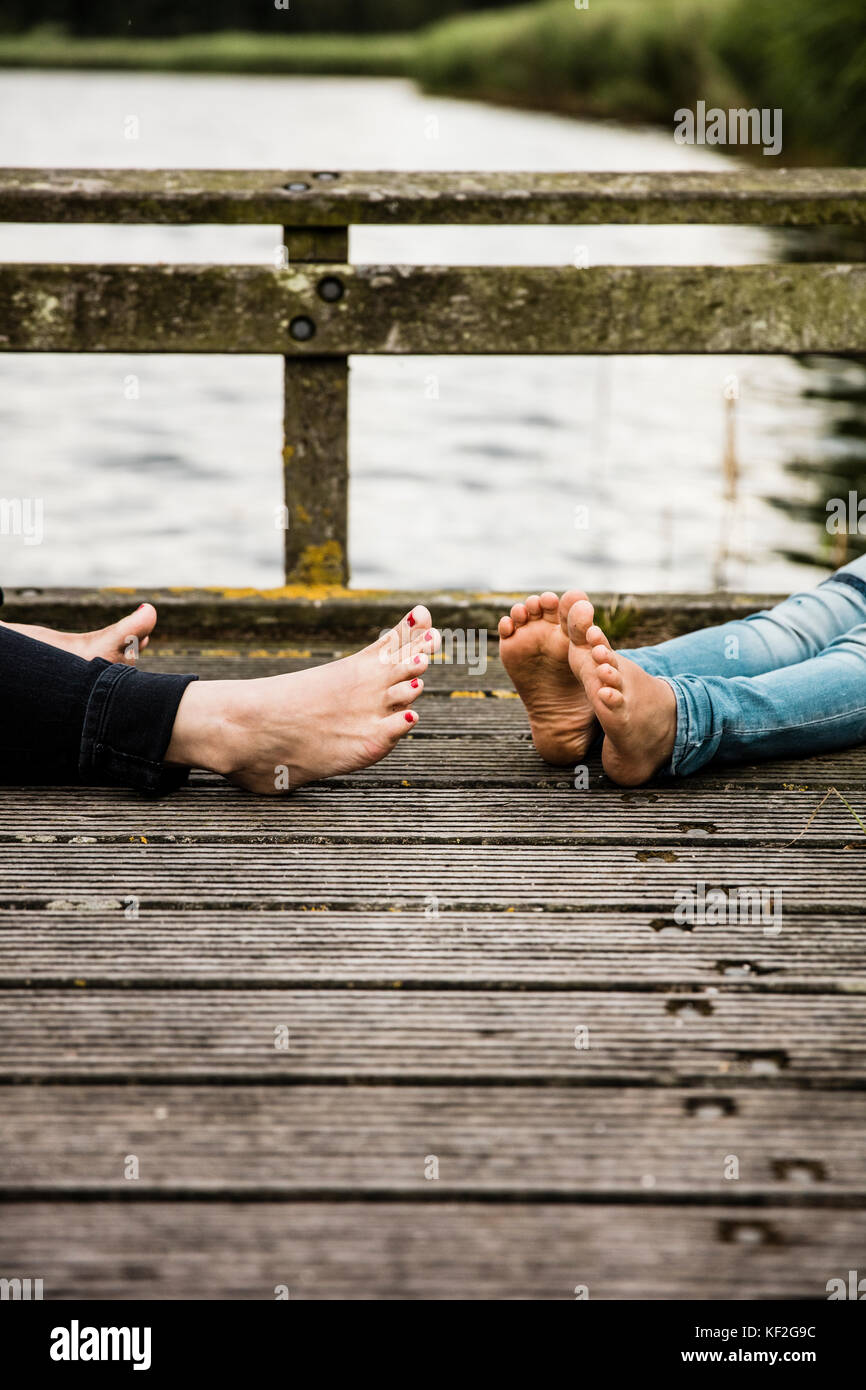 Füße von Mutter und Tochter am Steg am See Stockfoto