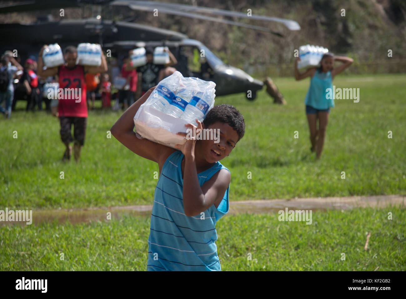Soldaten der US-Armee und lokale Freiwillige entladen während der Hilfsmaßnahmen nach dem Hurrikan Maria vom 4. Oktober 2017 in Jayuga, Puerto Rico, Wasser und Notvorräte aus einem HH-60 Black Hawk Hubschrauber. Stockfoto