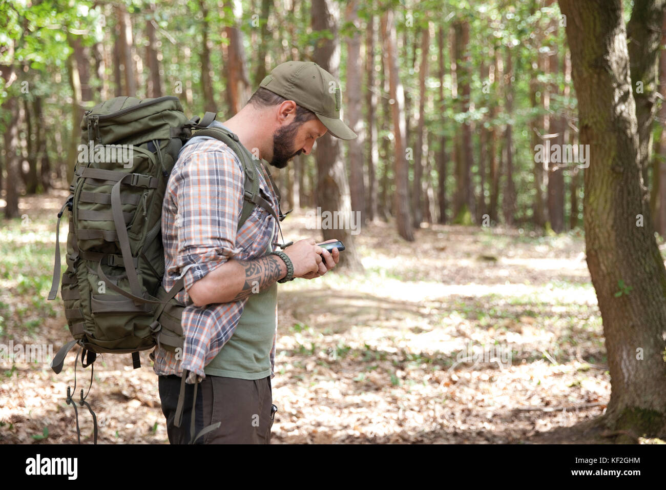 Mann mit Rucksack auf eine Wanderung im Wald mit Handy Stockfoto
