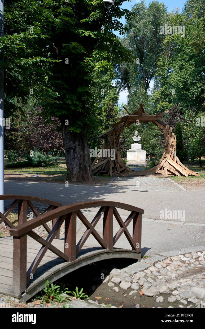 Ansicht der Büste (Statue) durch einen rustikalen Bogen mit kleinen hölzernen Brücke im Vordergrund im Central Park Cluj Stockfoto