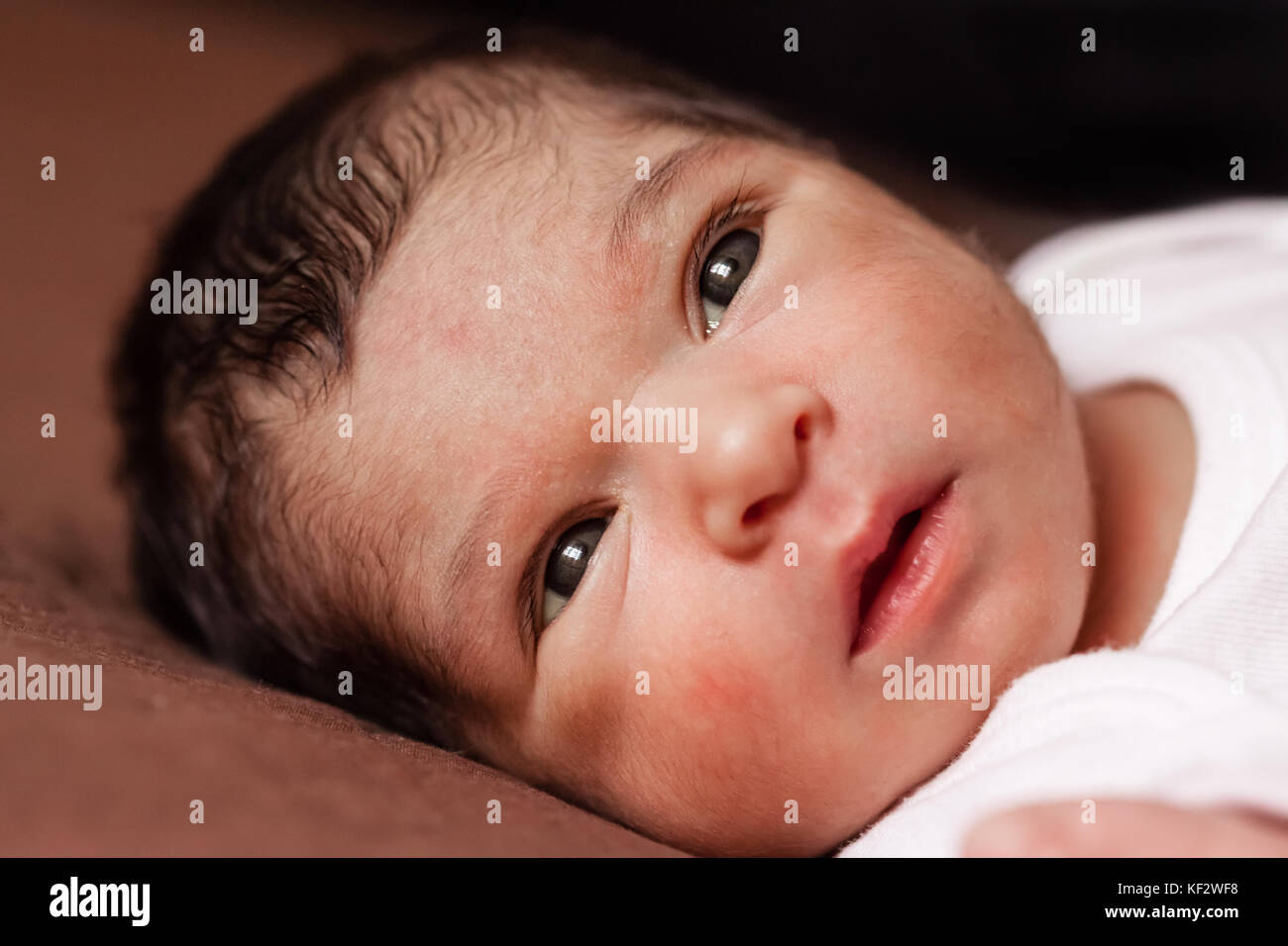 Nahaufnahme, Porträt einer niedlichen Zwei Wochen alte Neugeborene Mädchen liegend, die Augen öffnen und schauen um/neugeborenes Baby girl portrait liegend Bett Kind Stockfoto
