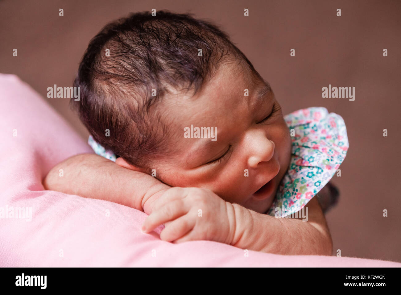 Nahaufnahme, Porträt einer niedlichen Zwei Wochen alte Neugeborene Mädchen mit einem geblümten Kleid, schlief friedlich über ein Kissen/Neugeborenen baby portrait cute Stockfoto