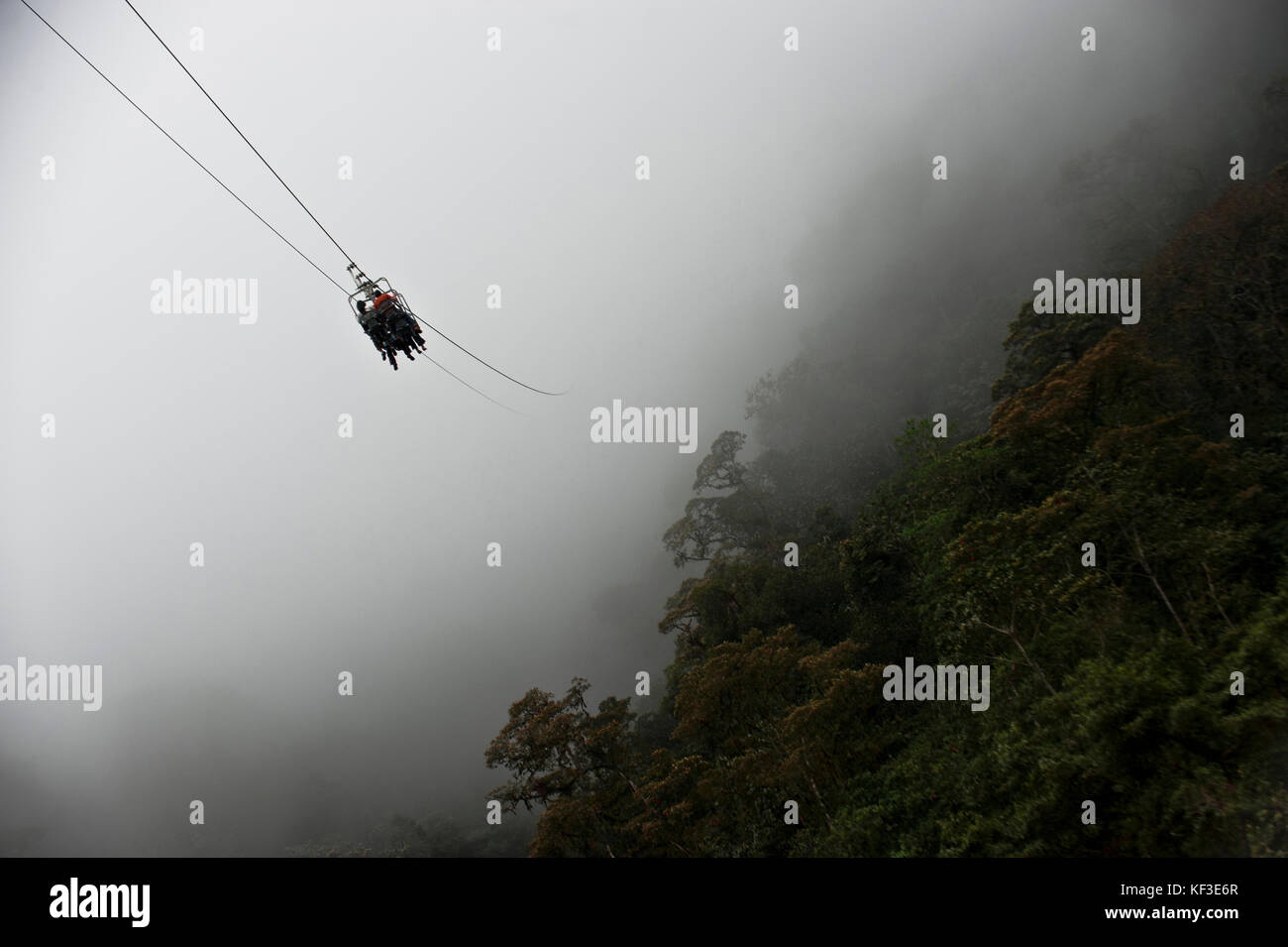Touristen gleiten auf die Zip Line auf einen Berg vor dem Hintergrund des Regenwaldes, Mindo, Ecuador Stockfoto