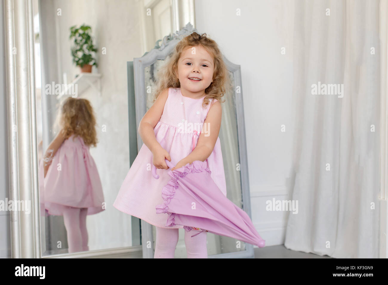 Adorable kleine Mädchen mit Schirm innen weiß Stockfoto