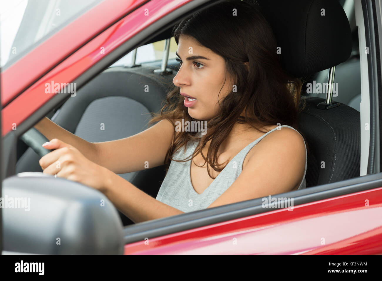 Close-up schockiert junge Frau sitzt im Auto Stockfoto