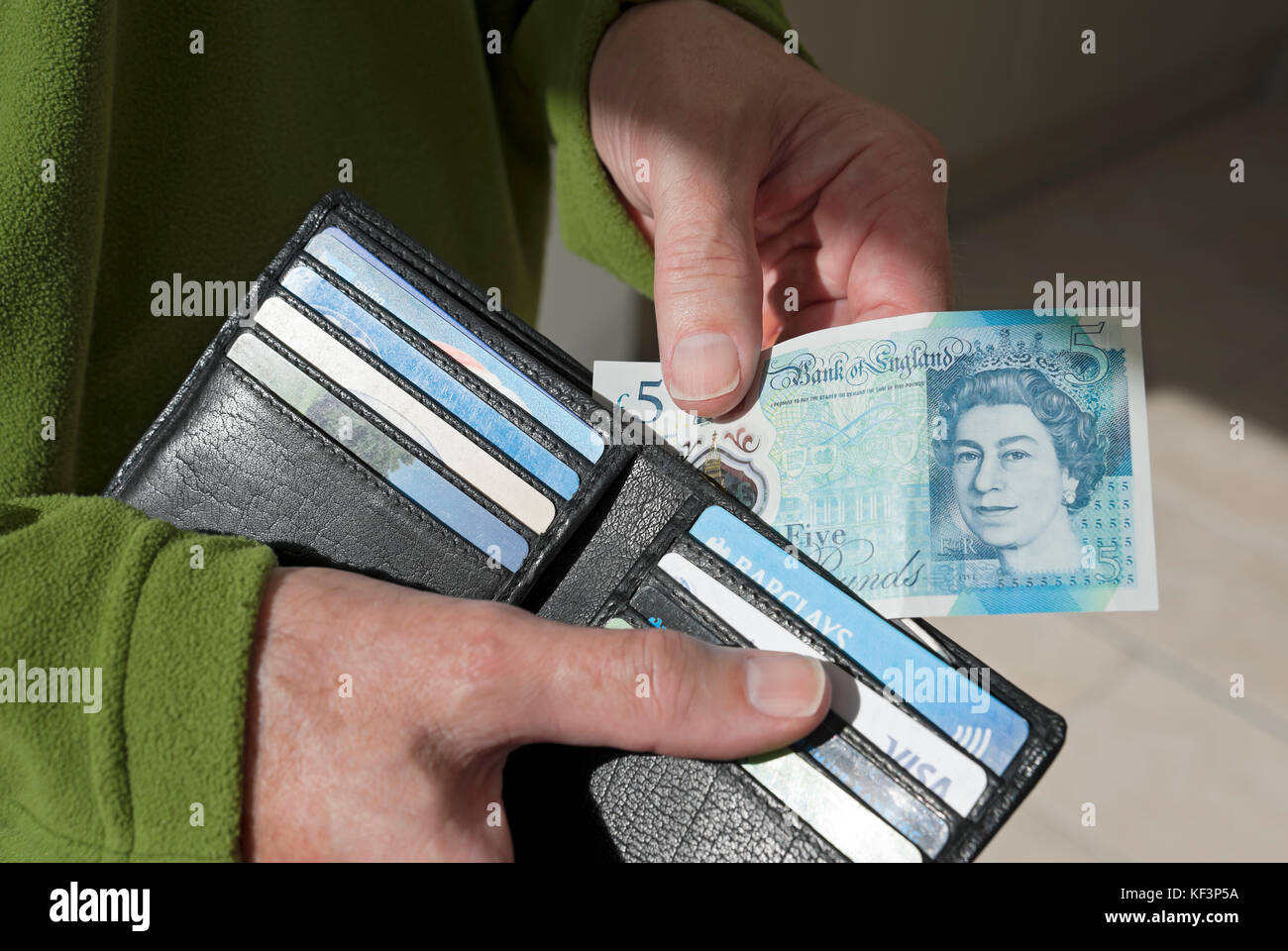 Nahaufnahme eines Mannes, der Bargeld nimmt neue £5 fünf-Pfund-Banknoten Englische Geldscheine aus der Brieftasche England Großbritannien GB Großbritannien Stockfoto