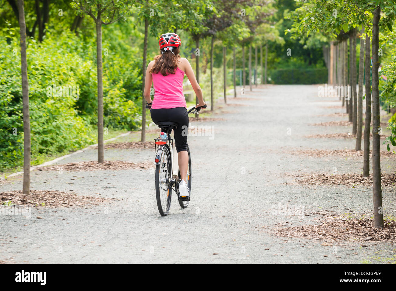 Junge weibliche Radfahrer reiten Weg auf Ihr Fahrrad mit Helm Stockfoto