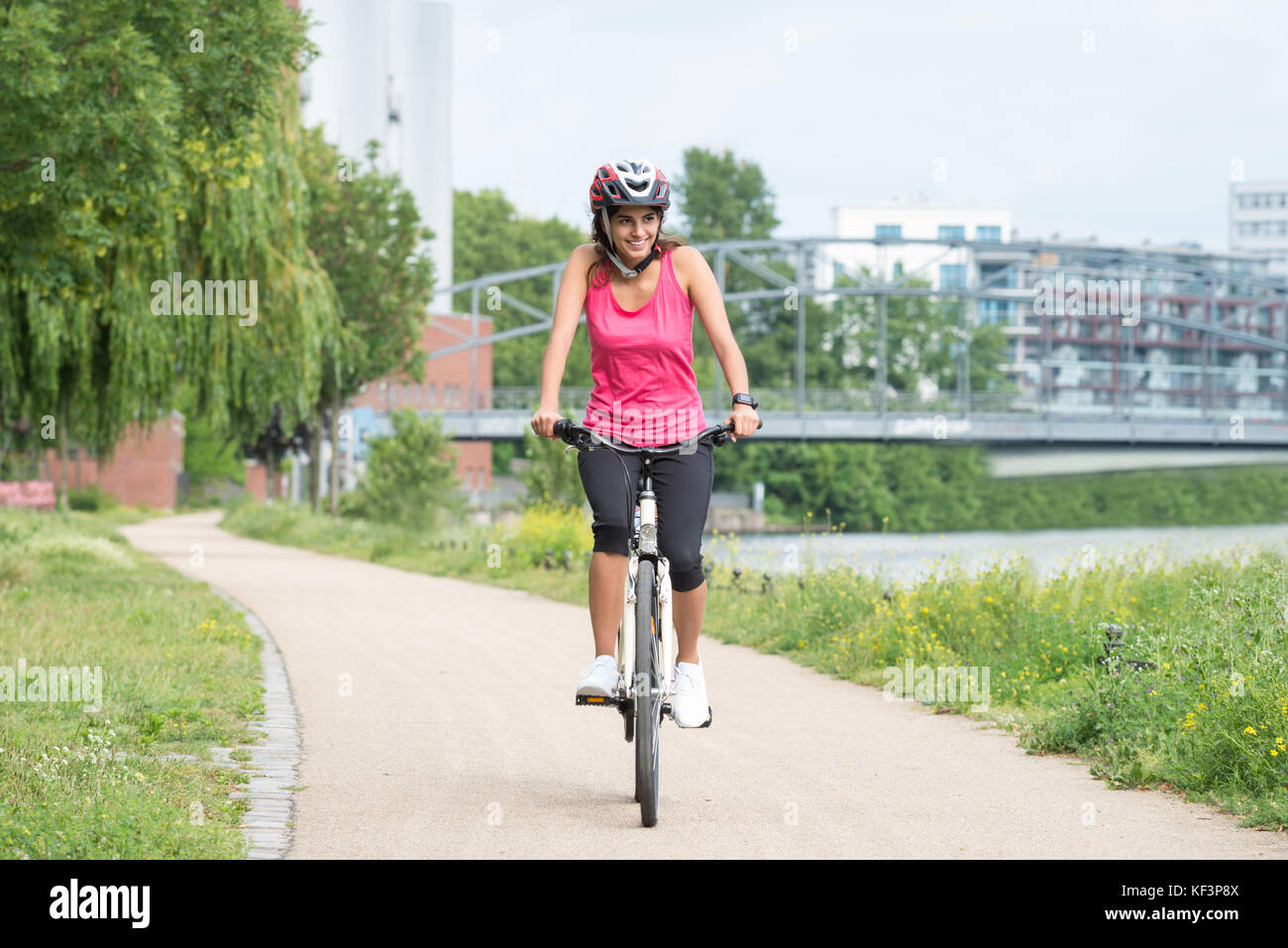Glückliche junge Frau mit Helm Reiten Fahrrad Stockfoto