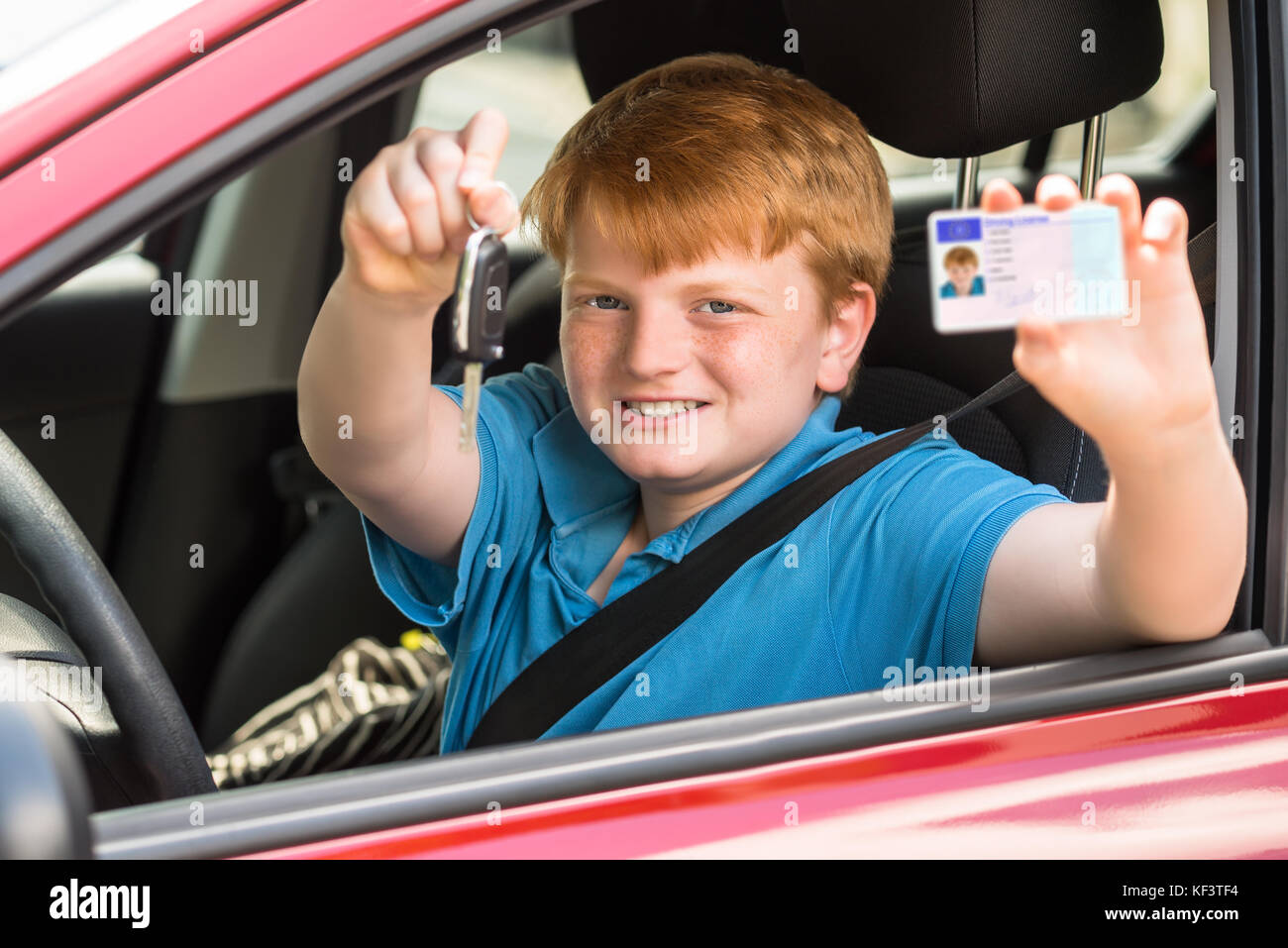 Glückliches Kind Sitzen im Auto, Schlüssel und Führerschein Stockfoto