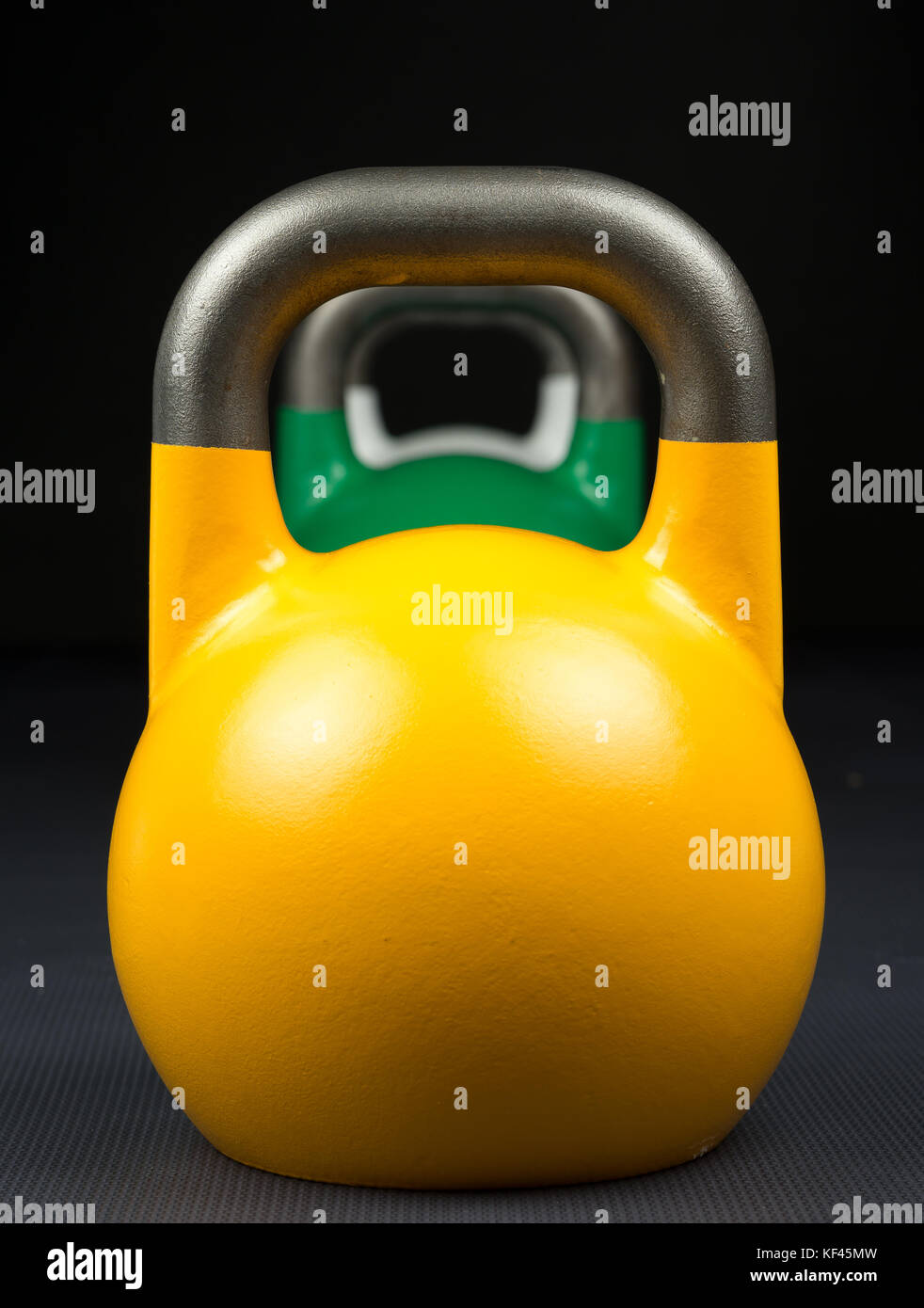 Gelb, Grün und Weiß Wettbewerb kettlebells stellten sich in einer Reihe auf ein Krafttraining Gym. Stockfoto