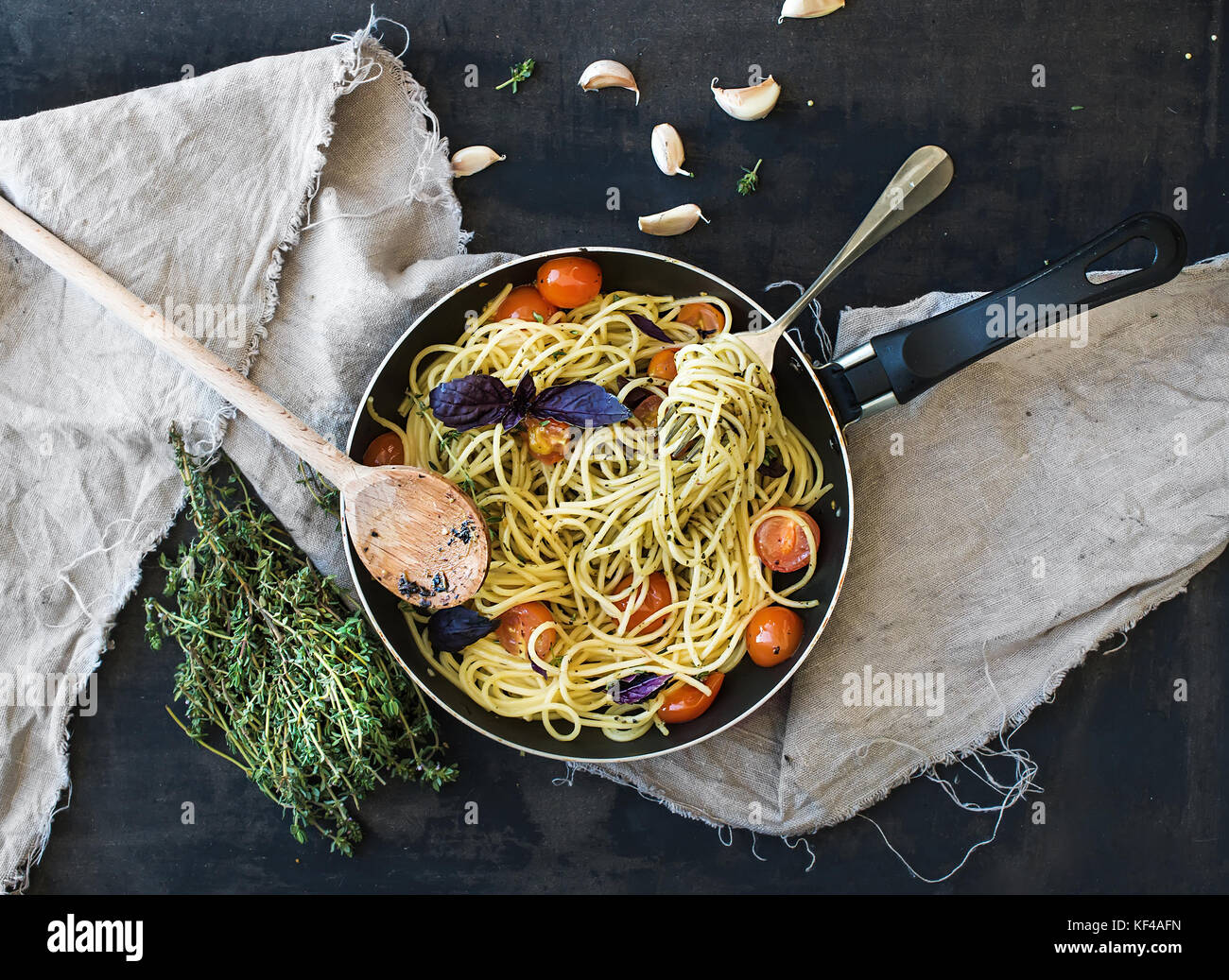 Pasta Spaghetti mit Pesto, Basilikum, Cherry-Tomaten, Knoblauch und Thymian in einem kochenden Topf Stockfoto