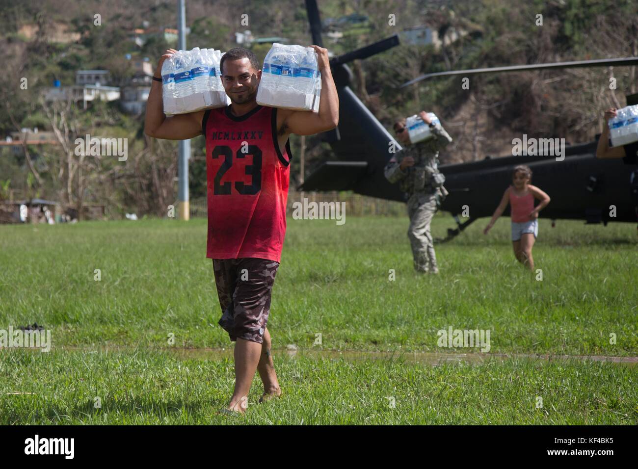 Soldaten der US-Armee und lokale Freiwillige entladen während der Hilfsmaßnahmen nach dem Hurrikan Maria vom 4. Oktober 2017 in Jayuga, Puerto Rico, Wasser und Notvorräte aus einem HH-60 Black Hawk Hubschrauber. Stockfoto