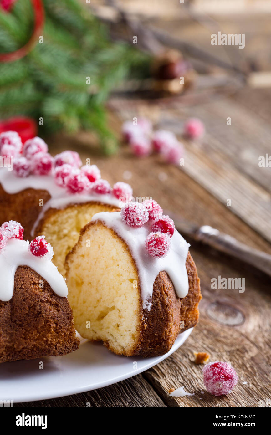 Kandierte Preiselbeeren bundt Cake mit Zitrone Zucker Glasur auf Holzbrett. hausgemachte Herbst und Winter gemütliches Dessert auf rustikalen Tisch Stockfoto