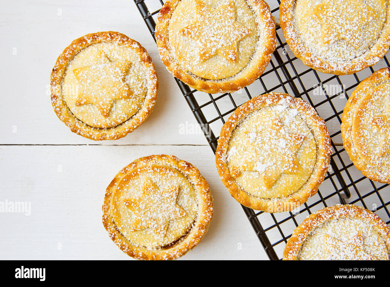 Traditionelle britische Weihnachten Backwaren dessert Hausgemachte mince pies mit Apple Rosinen Nüsse Füllung auf Kühlung Rack. golden Mürbteig weiß gepudert. Stockfoto