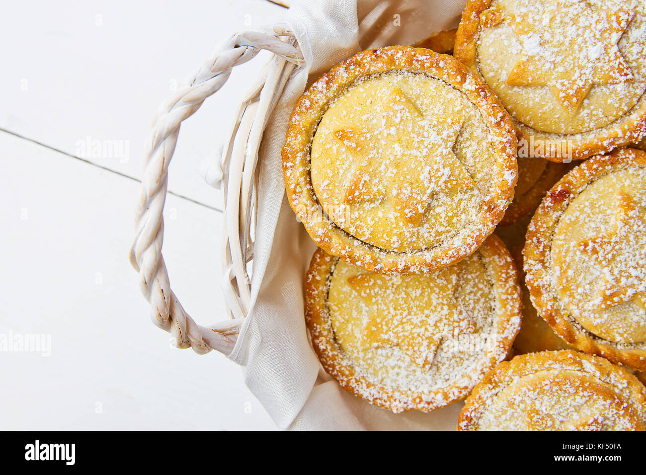 Traditionelle britische Weihnachten Backwaren dessert Hausgemachte mince pies mit Apple Rosinen Nüsse ausfüllen Weidenkorb. golden Mürbteig weiß gepudert. Stockfoto